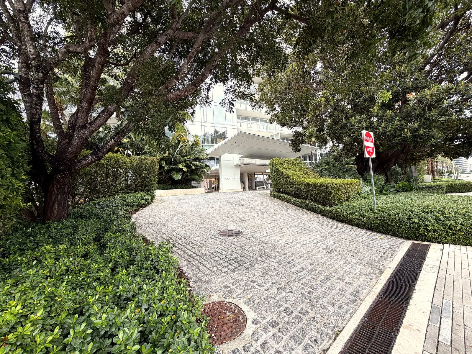 Cobblestone motor court with clipped hedges at a luxury property