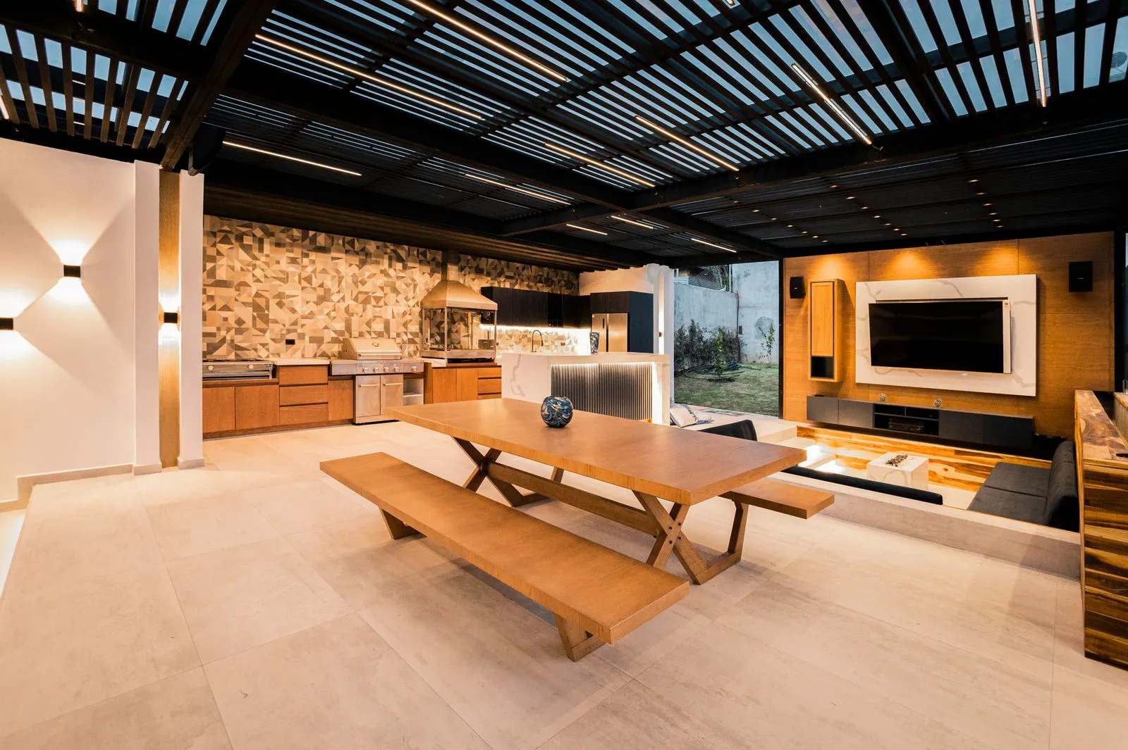 Louvered pergola over an outdoor kitchen and dining area